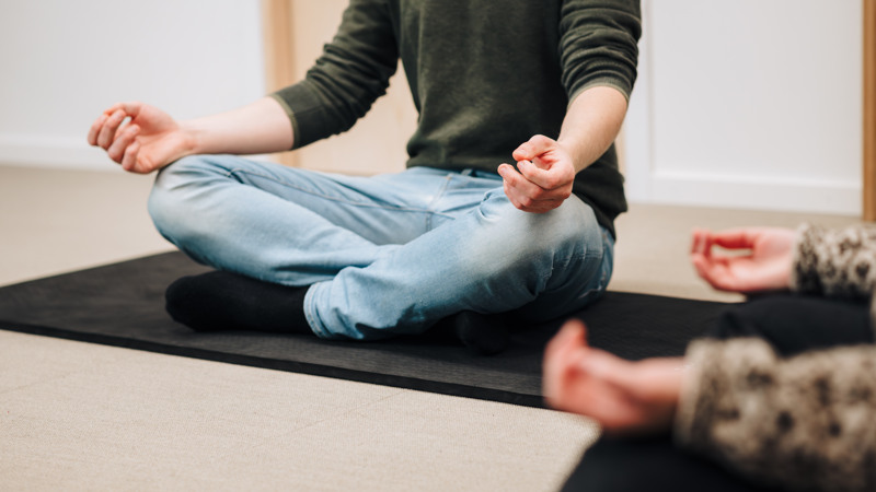 A man sitting in a lotus position on a yoga mat.