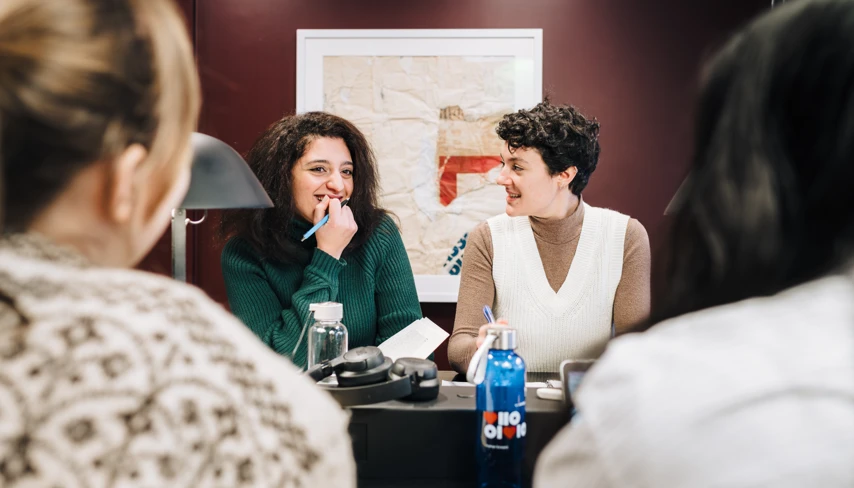 En grupp kvinnor som sitter runt ett bord och pratar.