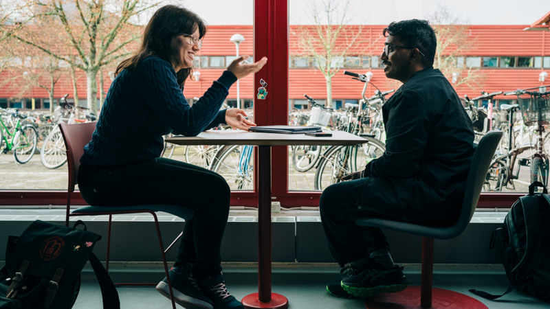 A man and a woman sitting at a table in front of a window.