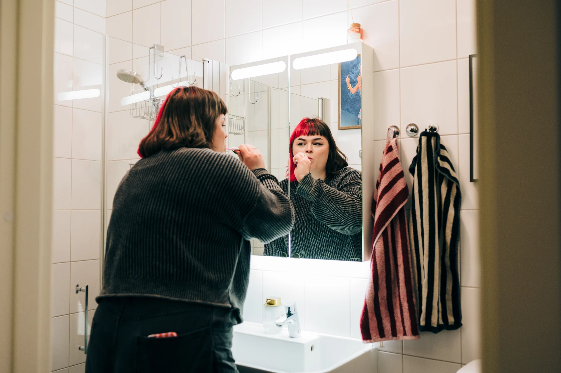 A woman brushing her teeth in front of a mirror.