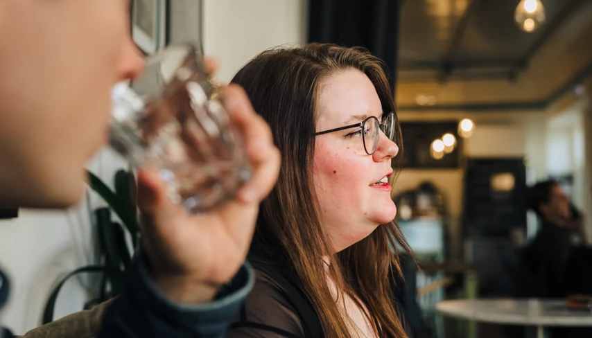 En man dricker ur ett glas bredvid en kvinna.