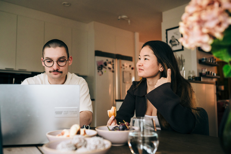 En man och en kvinna sitter vid ett bord och tittar p&aring; en b&auml;rbar dator.