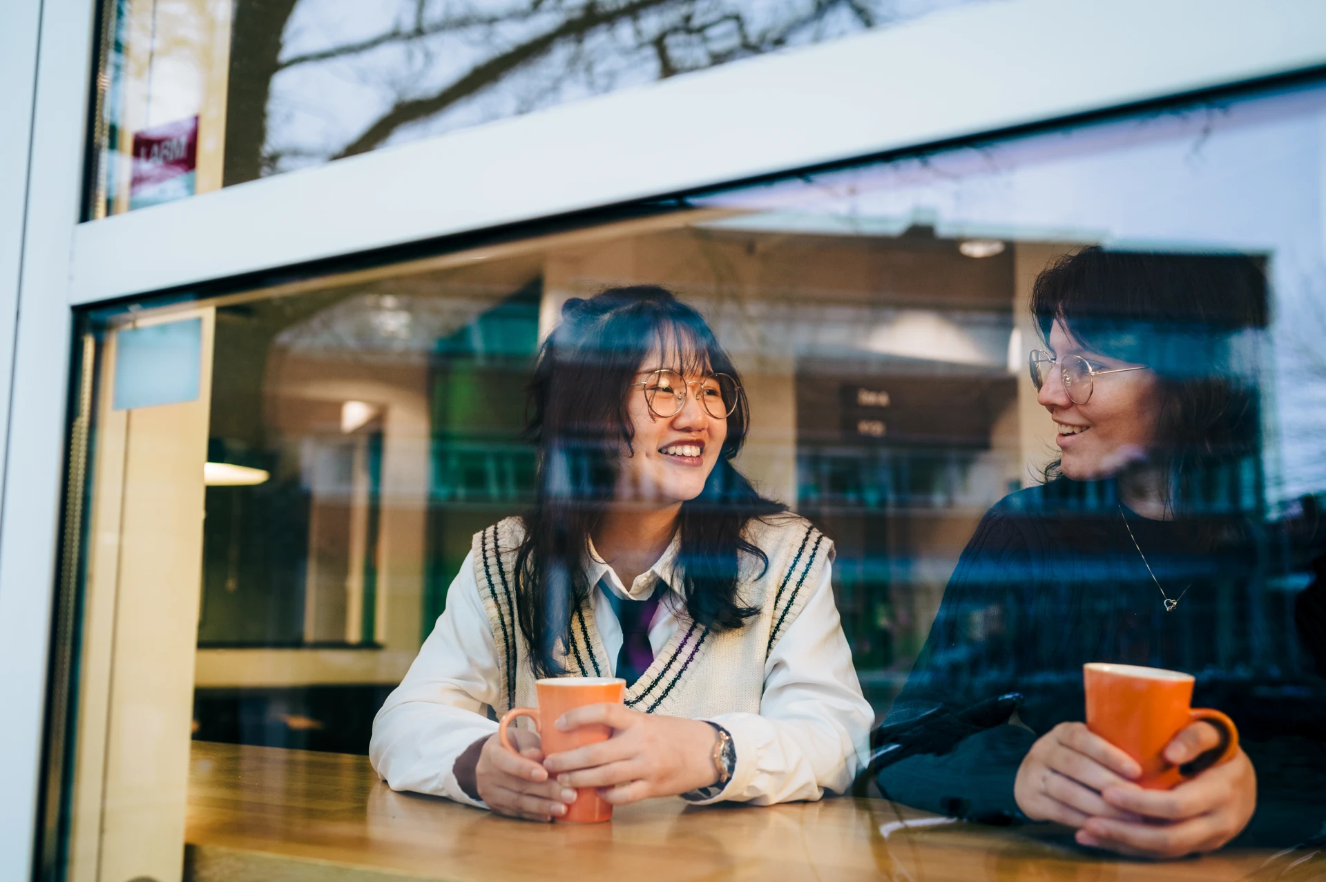 A couple of women sitting at a table next to each other.