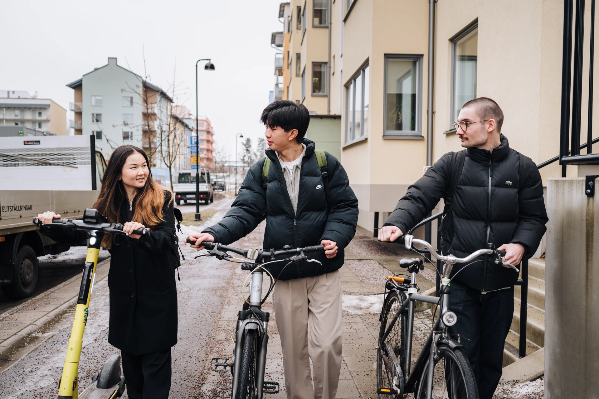 A group of people standing next to bikes on a street.