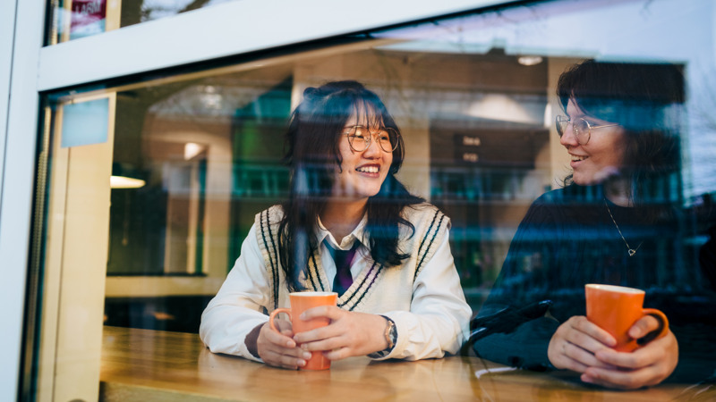 A couple of women sitting at a table next to each other.