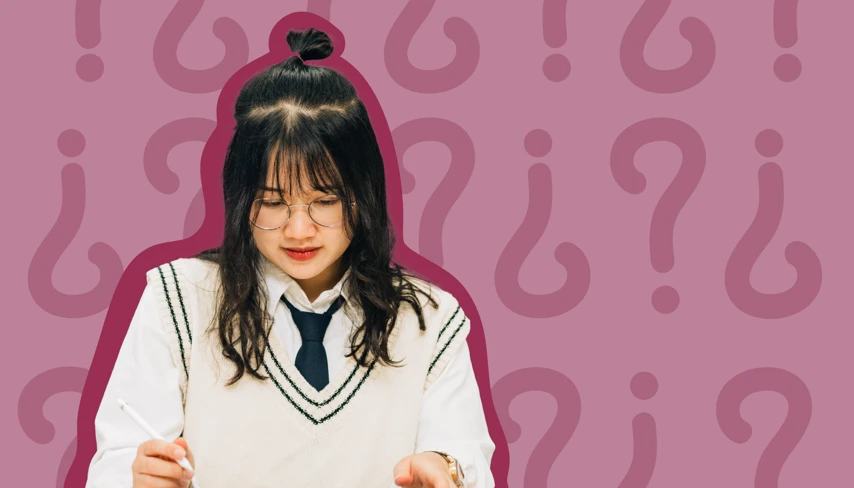 En flicka i skoluniform skriver på ett papper.